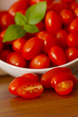 small tomatoes in white bowl with basil leaves