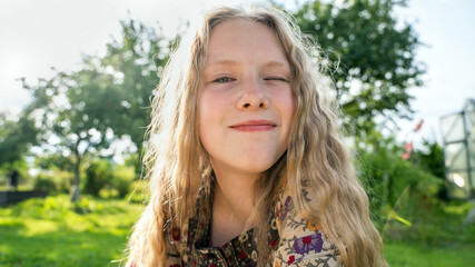 portrait of a  smiled girl with curly  blond hair  of twelve years old outdoor