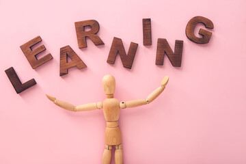 Wooden mannequin with word LEARNING on color background
