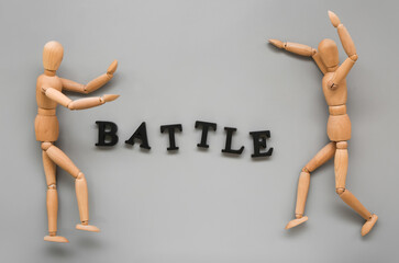 Wooden mannequins with word BATTLE on grey background