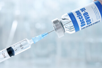 Syringe taking covid 19 corona virus liquid vaccine from vial bottle testing and preparing for...