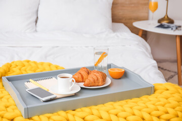 Obraz na płótnie Canvas Tray with tasty breakfast and mobile phone on bed