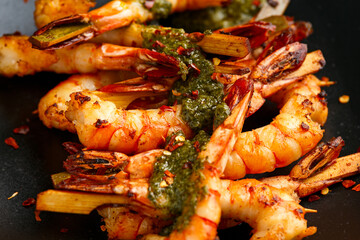 Grilled Tiger prawns skewers with garlic coriander and chili served on black plate