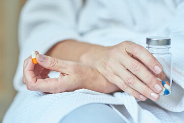 Woman with crossed hands holding pill and pill bottle