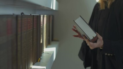Woman Lawyer pulls a book from the shelf of the library in her office. browsing the pages of the book