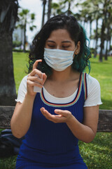 mujer desinfectando la mano en el parque.