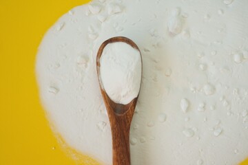 Baking soda.Sodium bicarbonate on a wooden spoon  on a  yellow background.Food supplement. Organic hypoallergenic cleaning agent.Zero waste concept
