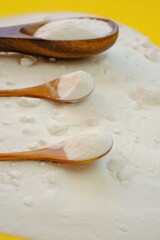 Baking soda.Sodium bicarbonate on a wooden spoon set on a bright yellow background.Food supplement. Organic hypoallergenic cleaning agent.Zero waste 