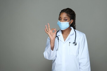 Portrait of an African American  doctor in white robe and showing ok gesture