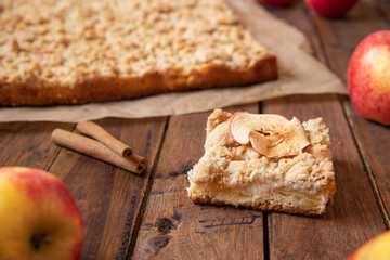Kuchen mit Äpfeln als Füllung und Streusel auf einem braunen Tisch aus Holz in der Küche
