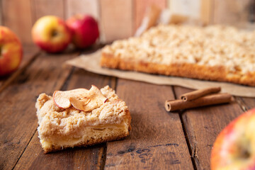 Kuchen mit Äpfeln als Füllung und Streusel auf einem braunen Tisch aus Holz in der Küche