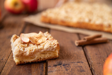 Kuchen mit Äpfeln als Füllung und Streusel auf einem braunen Tisch aus Holz in der Küche