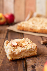 Kuchen mit Äpfeln als Füllung und Streusel auf einem braunen Tisch aus Holz in der Küche