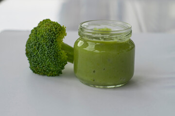 Broccoli puree in a glass jar for introducing the first complementary foods to the baby. Children's healthy food.