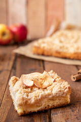 Kuchen mit Äpfeln als Füllung und Streusel auf einem braunen Tisch aus Holz in der Küche