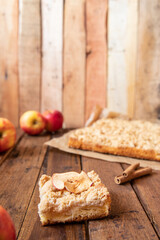 Kuchen mit Äpfeln als Füllung und Streusel auf einem braunen Tisch aus Holz in der Küche