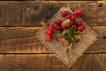 Sprigs of ripe rose hips on a burlap napkin on a wooden table. Harvesting of wild rose berries for...