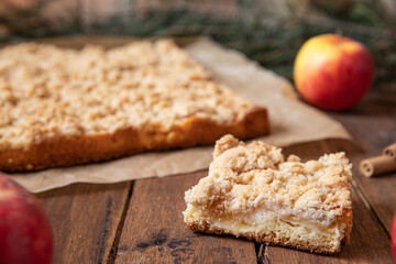 Kuchen mit Äpfeln als Füllung und Streusel auf einem braunen Tisch aus Holz in der Küche