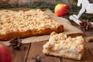 Kuchen mit Äpfeln als Füllung und Streusel auf einem braunen Tisch aus Holz in der Küche