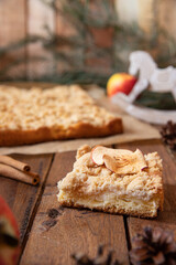 Kuchen mit Äpfeln als Füllung und Streusel auf einem braunen Tisch aus Holz in der Küche
