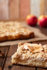Kuchen mit Äpfeln als Füllung und Streusel auf einem braunen Tisch aus Holz in der Küche