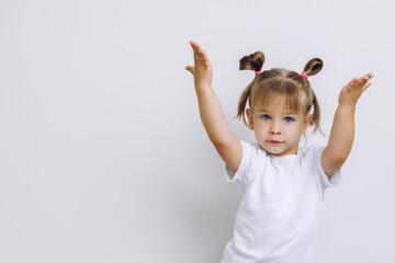 emotional little girl on a light flat background. the child raised his hands up inviting the...