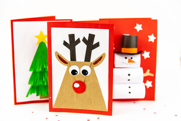DIY Christmas cards kids. Three cards with a Christmas tree, a deer, a snowman from colored paper.