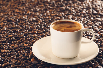 Cup of hot coffee on roasted beans