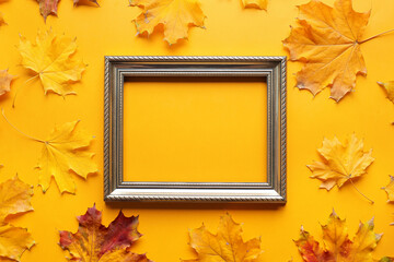 Naklejka na ściany i meble Frame and autumn leaves on color background