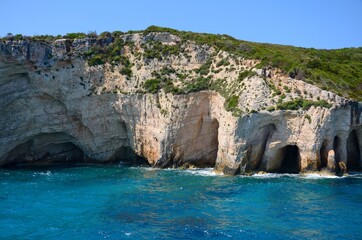 Fototapeta na wymiar Blue cave on Zakynthos island. Crystal clear water, boat trip around the island of Zakynthos. Caves on the coast created by the sea. Limestone cliffs.