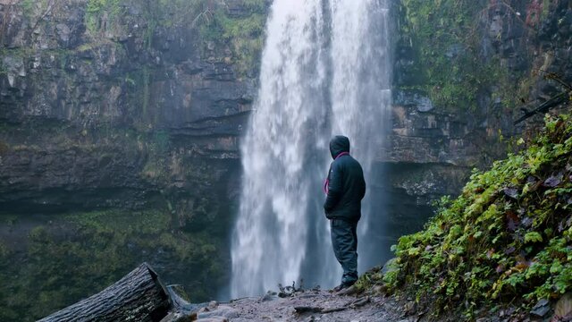 Male stood infront of water fall at henrhyd falls during the winter. South Wales uk. also known for the iconic film batman
