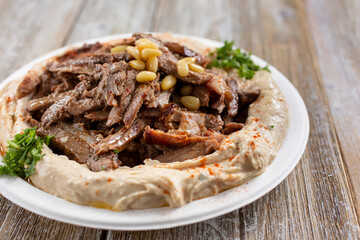 A view of a plate of hummus, topped with beef shawarma.
