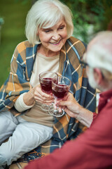 Smiling senior woman with plaid on her shoulders looking at spouse