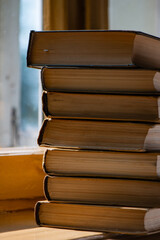Fototapeta premium stack of old books lies on the background of a window on a sunny day.