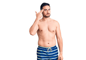 Fototapeta premium Young handsome man wearing swimwear shooting and killing oneself pointing hand and fingers to head like gun, suicide gesture.