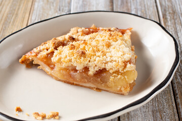 A view of a slice of apple crumble pie on a plate. 