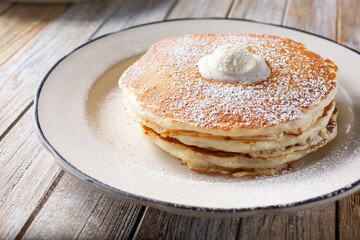 A view of a plate of pancakes, topped with a mound of whipped butter.