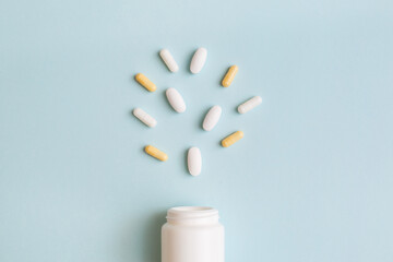 Creative medical layout made with pharmaceutical medicine pills, tablets, capsules, vitamins and bottle on light blue background. Minimal pharmacy or health care concept. Flat lay, top view,copy space
