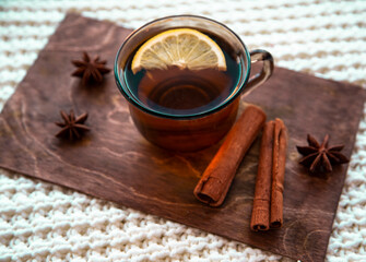 Cup of tea with lemon on a wooden stand with cinnamon and star anise