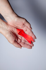 healthcare and medicine concept - female hands holding red AIDS awareness ribbon.
