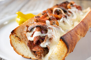 A closeup view inside a grilled mushroom and steak hoagie sandwich.