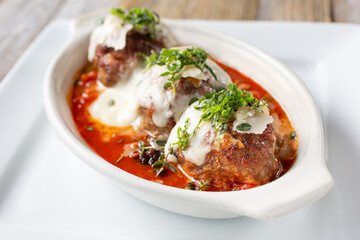 A view of a casserole dish with rustic large meatballs in marinara sauce.