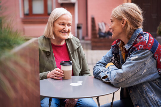 Daughter sitting at the outdoor cafe with her senior mother