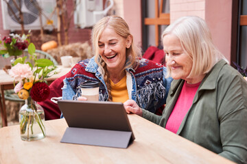 Woman and her adult daughter looking at the digital tablet