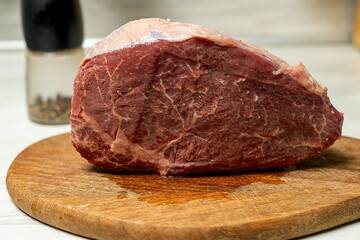 Raw aged beef ribeye steak on bamboo chopping board.