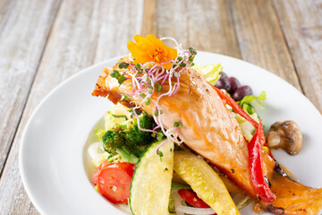 A view of a salmon filet over a bed of grilled vegetables.
