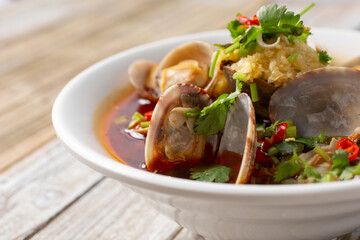  A view of a bowl of spicy clam soup, in a restaurant or kitchen setting.