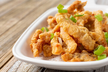 A closeup view of a plate of deep fried pork, in a restaurant or kitchen setting.