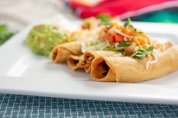 A closeup view of a plate of taquitos.