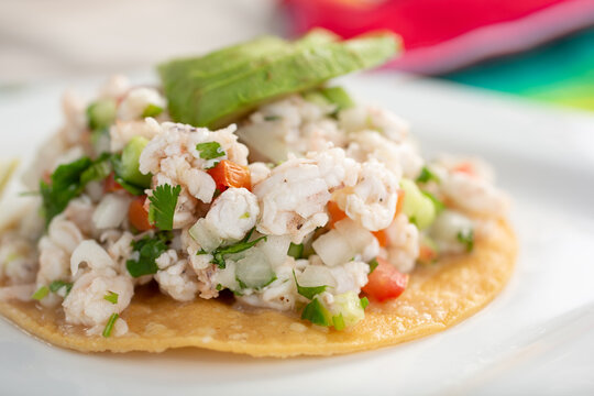 A closeup view of a plate of shrimp tostada, in a restaurant or kitchen setting.